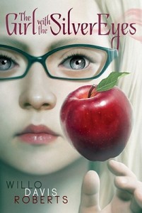 Cover of "The Girl with the Silver Eyes," featuring a girl with blond hair, glasses, and gray eyes staring at an apple that is hovering in front of her face