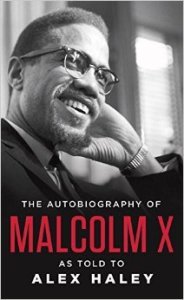 Cover of "The Autobiography of Malcolm X," featuring a black-and-white picture of Malcolm X, a light-skinned black man, as he looks into the distance and smiles.