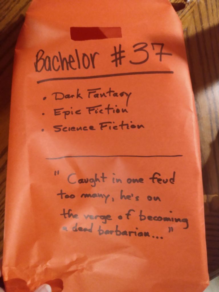 Package wrapped in red paper with black handwriting that reads:
Bachelor #37
Dark fantasy
Epic fiction
Science fiction
"Caught in one feud too many, he's on the verge of becoming a dead barbarian..."